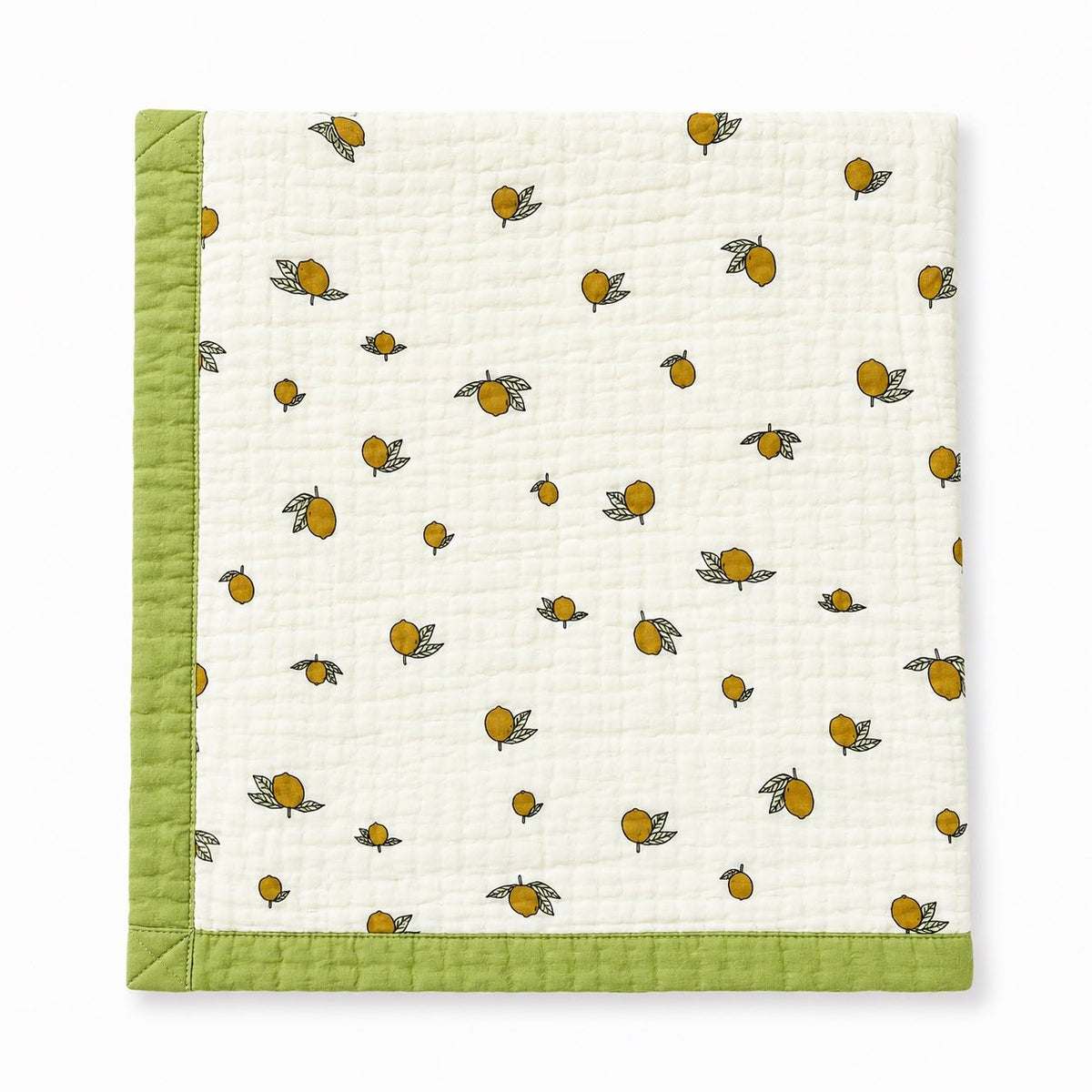 A square quilted baby blanket with a white textured fabric body, printed with small yellow-orange lemons and green leaves, finished with a solid light green stitched border.
