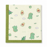A square quilted baby blanket with a green border and a playful pattern of green cartoon dinosaurs, avocado halves, clouds, and small trees on a warm cream background.