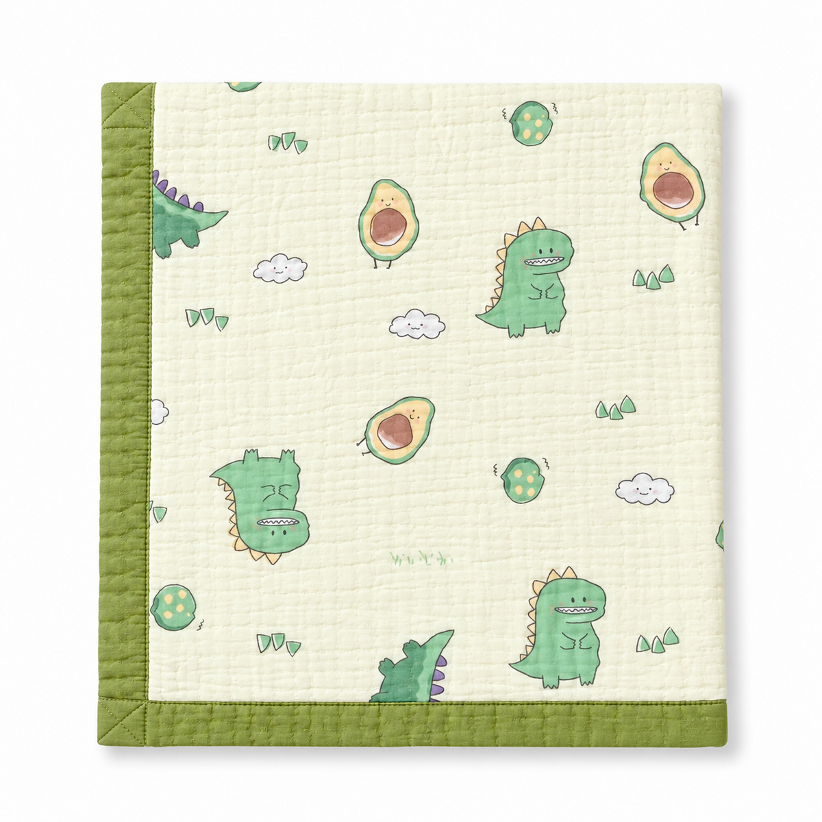 A square quilted baby blanket with a green border and a playful pattern of green cartoon dinosaurs, avocado halves, clouds, and small trees on a warm cream background.