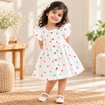 My Mini Buds white muslin baby girl frill frock with red and green heart print, layered ruffle sleeves and a button-down front.Toddler girl wearing 